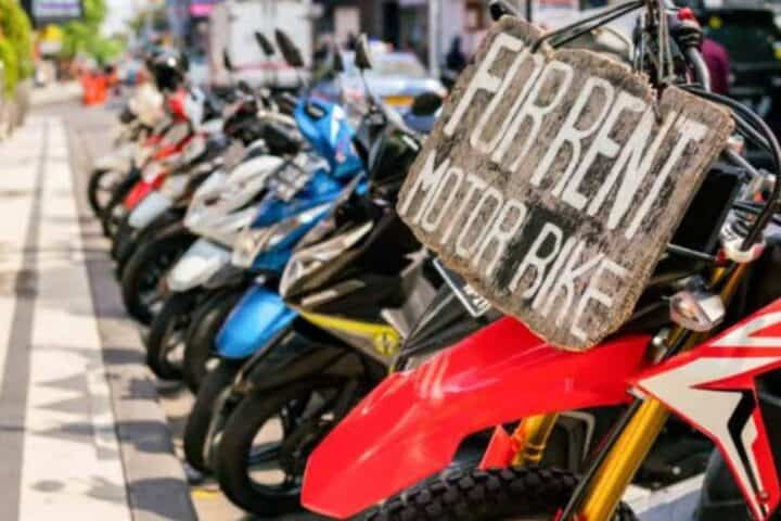 Row of colorful scooters with a wooden &ldquo;For Rent Motor Bike&rdquo; sign on the street in Canggu Bali &ndash; GoTravela Indonesia